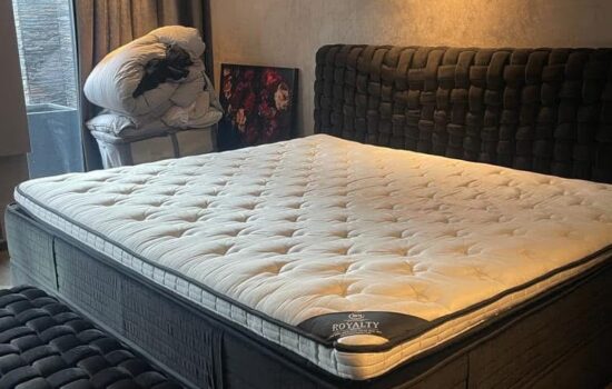 Een persoon die een matras grondig reinigt met een stofzuiger en een speciale matrasreiniger, terwijl ze aandacht besteden aan het verwijderen van vlekken en allergenen, in een lichte en schone slaapkamer.